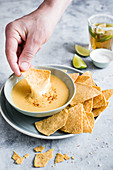 Dipping corn chips in cheese sauce