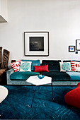 Comfortable sofa with scatter cushions and slender coffee table on blue carpet in living room