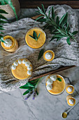 Tasty aromatic mango mousse in glass mugs and spoon on table decorated with green plants