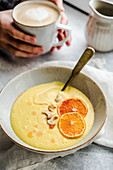 Orange millet pudding with red oranges and cashews served with coffee