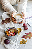 Autumn time, warming up millet with fruit, coffee in the hands of a person dressed in a warm sweater