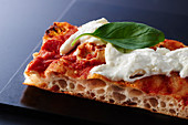 A piece of pizza with burrata and basil