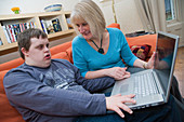 Mother and teenage son with Down Syndrome using a laptop