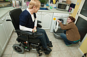 Daughter loading washing machine while mother watches