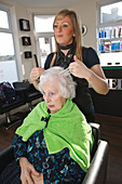 Hairdresser styling old lady's hair