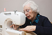 Elderly woman using sewing machine