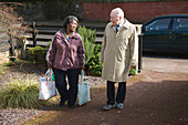 Carer carrying shopping for pensioner