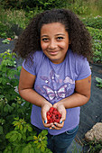 Girl with handful of raspberries