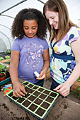 Woman with daughter planting seeds in a tray