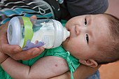 Chinese baby being fed from a bottle