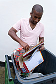 Man putting cardboard in recycling wheelie bin