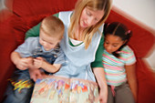 Nursery nurse reading book with children