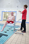 Disabled man being lowered into swimming pool