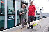 Vision impaired man with sighted guide and guide dog
