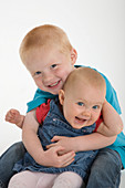 Portrait of a baby sister and brother laughing
