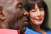 Elderly black man with carer at home chatting