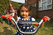 Girl on trike with mother behind