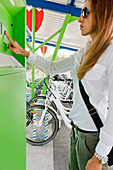 Young woman using electric bicycle sharing system