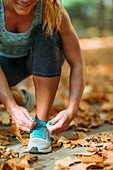 Woman kneeling and tying shoe