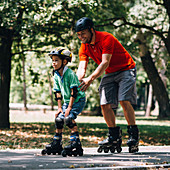 Father teaching son to roller skate in park