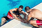 Lifeguards with woman on poolside