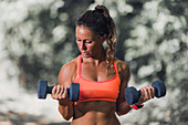 Woman exercising with dumbbells outdoors