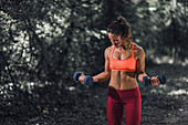 Woman exercising with dumbbells outdoors