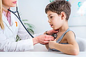 Paediatrician examining boy with stethoscope