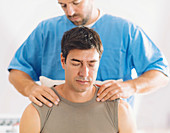 Physiotherapist massaging man's shoulders