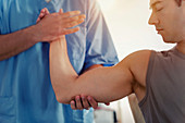 Physiotherapist stretching man's arm