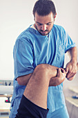 Physiotherapist stretching man's leg