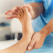 Physiotherapist stretching man's foot