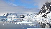 Ship in Antarctic sea with mountains