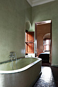 Masonry bathtub in Mediterranean bathroom with green walls