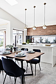 Set dining table, elegant chairs and kitchen island in open-plan interior