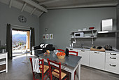 Table and chairs in kitchen with grey walls and access to terrace