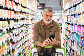 Man using a smartphone in supermarket