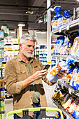 Man using an app on his smartphone in a supermarket