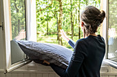 Woman beating pillows at the window