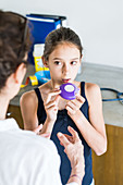 Doctor instructing a girl on how to use asthma inhaler