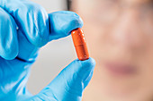 Scientist holding orange pill