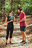 Young couple looking at their smart watches after training