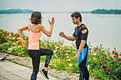 Female exercising by the river with personal trainer