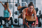 Female athlete using lying leg curl bench in the gym