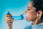 Woman using asthma inhaler with extension tube