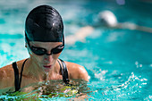 Woman swimming breaststroke in indoor pool