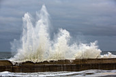 Waves breaking over harbour wall