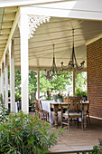 Wooden table and chairs on roofed terrace with carved ornamentation