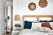 Double bed with wooden headboard against white wooden wall