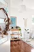 Wreath of dried plants on door and rattan shelves in white living room